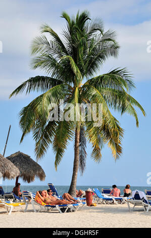 Bathers and palm trees on the beach of Playa Ancón, near Trinidad, Cuba, Caribbean Stock Photo