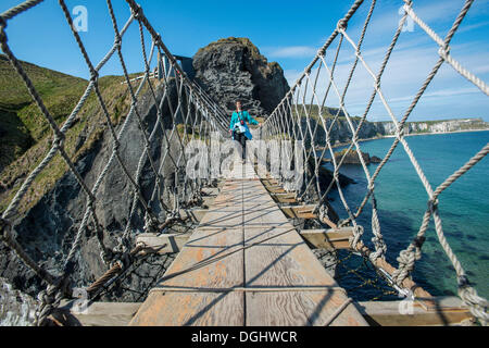 Woman walking across the Carrick-a-Rede Bridge, suspension bridge, Moyle, Northern Ireland, United Kingdom, Europe Stock Photo