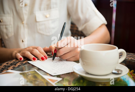 Woman writing postcard in cafe Stock Photo