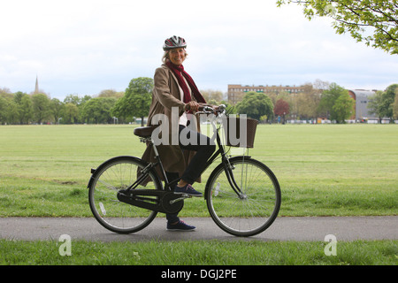 Senior woman riding bicycle in park, portrait Stock Photo