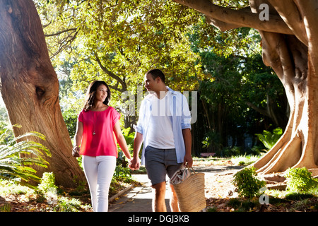 Young couple walking on path through trees Stock Photo