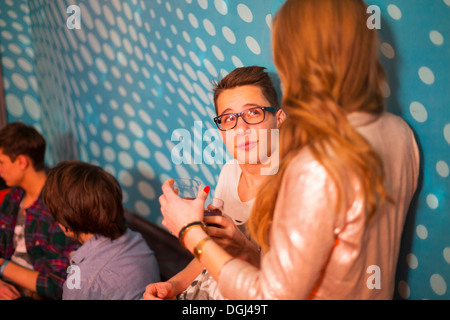 Teenage boy looking up at teenage girl, friends in background Stock Photo