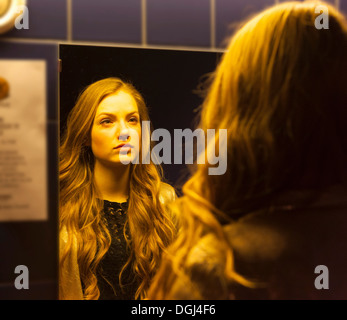 Teenage girl looking at her reflection in mirror Stock Photo