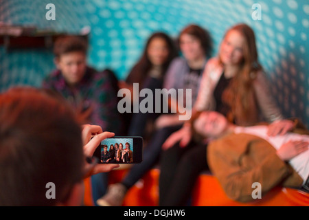 Teenage boy taking photo of group of friends using smartphone Stock Photo