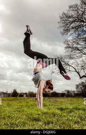 Woman doing handstand with legs apart