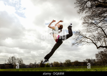 Woman jumping in mid air with bent leg Stock Photo