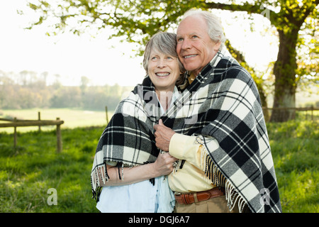 Senior couple wrapped in shawl together Stock Photo