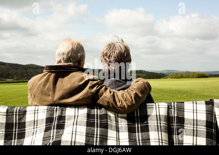 Back view of senior couple enjoying scenery on field Stock Photo