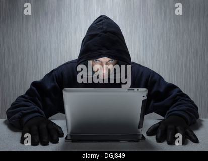 A hooded man representing a cyber criminal. Stock Photo