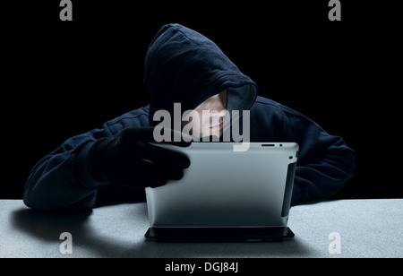 A hooded man representing a cyber criminal. Stock Photo