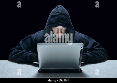 A hooded man representing a cyber criminal. Stock Photo