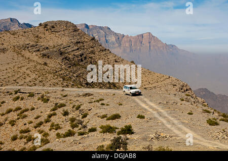 Off-road vehicle on a track in the rugged mountain landscape at the Sharaf al Alamayn Pass, Oman Stock Photo