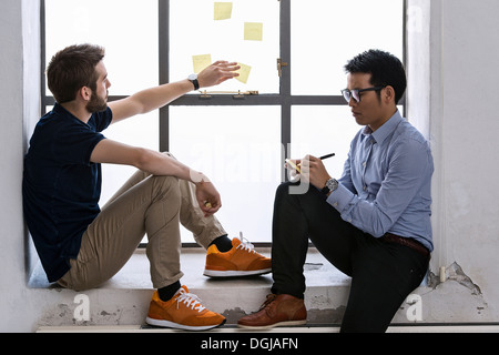 Two young male designers sharing ideas on post it notes Stock Photo