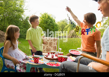 Family with two children celebrating birthday outdoors Stock Photo