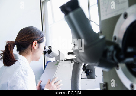 Female scientist looking through microscope Stock Photo