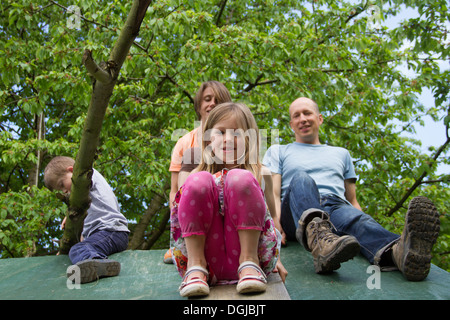 Family with two children sitting on playhouse roof Stock Photo