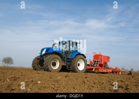 Tractor pulling equipment to plant seeds in field Stock Photo