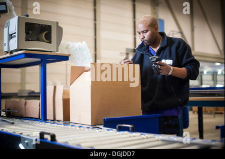 Male warehouse worker checking cardboard box Stock Photo