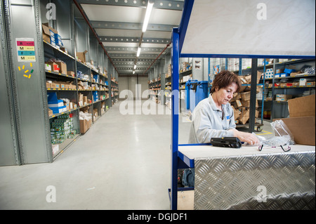 Female warehouse worker preparing orders on delivery trolley Stock Photo