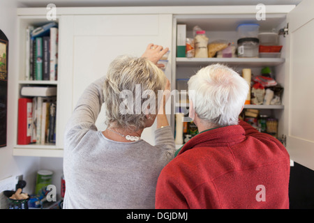 Senior couple checking kitchen cupboards Stock Photo