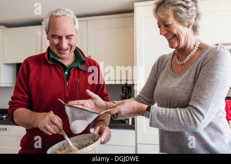 Senior couple sieving flour into mixing bowl Stock Photo