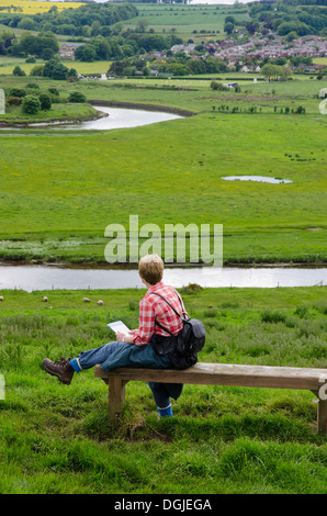 Woman walker on seat overlooking the river Aln. Stock Photo