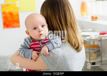 Mother holding baby son over shoulder Stock Photo
