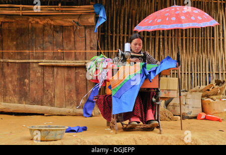 Young Vietnamese woman sewing costumes of the Hmong ethnic minority, old mechanical sewing machine, Flower Hmong ethnic group Stock Photo