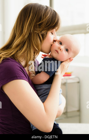 Mother kissing baby son on cheek Stock Photo