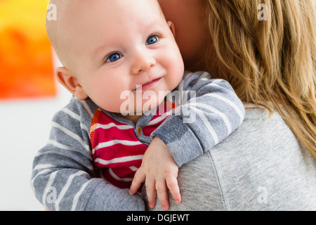 Mother holding baby son over shoulder Stock Photo