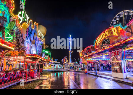 Ghost train, bumper cars and the No Limit XXL funfair ride at night after a heavy shower, Suedring amusement park, Innsbruck Stock Photo