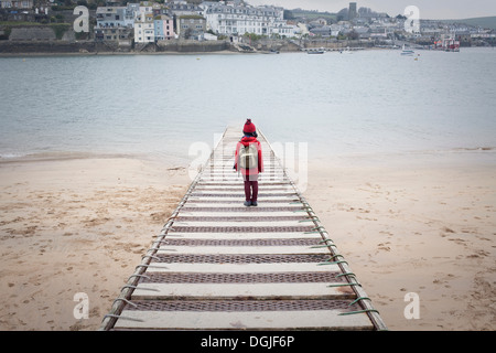 Rear view of boy standing on pier overlooking sea Stock Photo