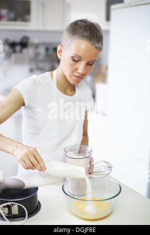 Woman pouring sugar into mixing bowl Stock Photo