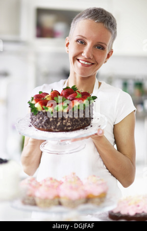 Portrait of woman holding cake with strawberries Stock Photo