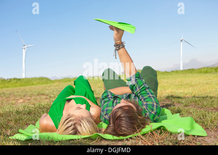 Young couple lying in field, man holding paper aeroplane Stock Photo