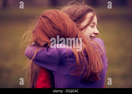 Young friends embracing outdoors Stock Photo