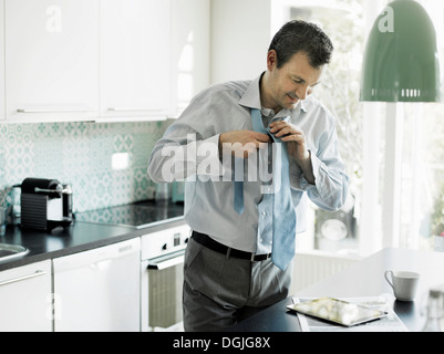 Mature businessman getting ready and using tablet in kitchen Stock Photo