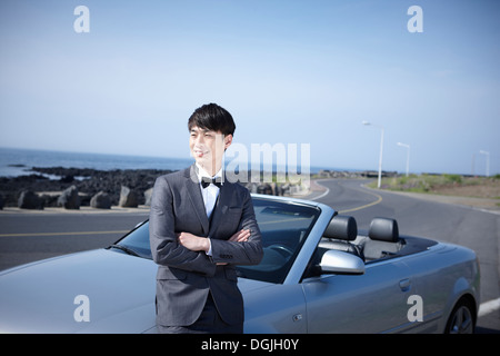 a groom standing next to a car Stock Photo