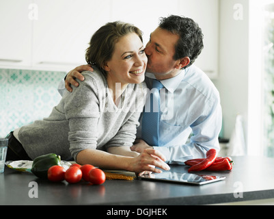 Businessman kissing wife in kitchen Stock Photo