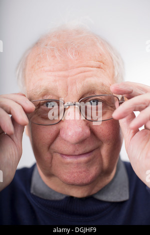 Portrait of senior man adjusting glasses, studio shot