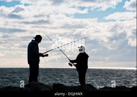 Two anglers fishing off rocks near Cottesloe Beach in Perth in Western Australia. Stock Photo