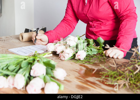 Close up of young woman arranging roses in florists Stock Photo