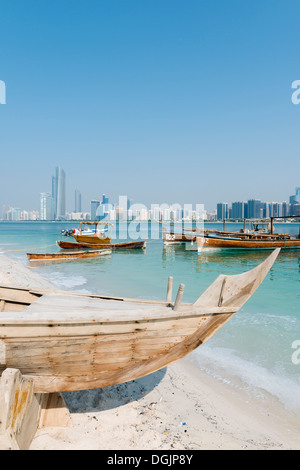 Skyline of modern Abu Dhabi and old traditional fishing boats in Heritage Village in Abu Dhabi in United Arab Emirates UAE Stock Photo