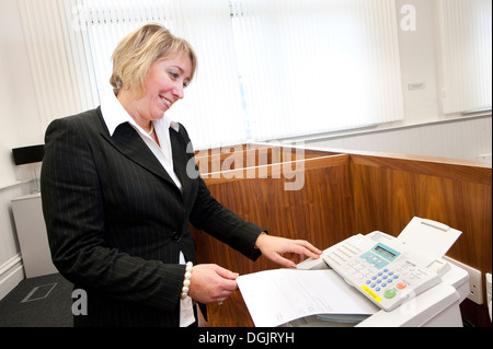 Businesswoman using a fax machine. Stock Photo