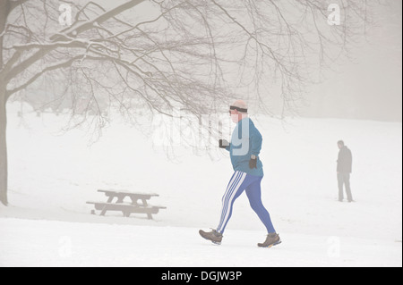 A middle aged man jogging through freezing fog and snow. Stock Photo