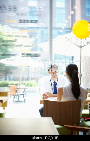 a man and a woman talking at a table Stock Photo