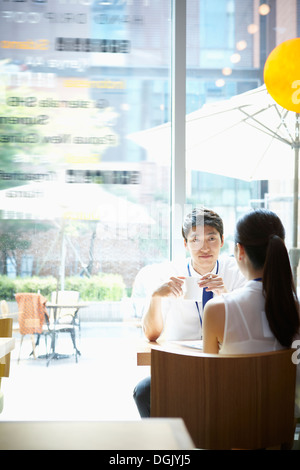 a man and a woman talking at a table Stock Photo