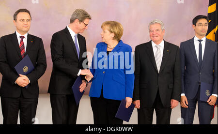 Berlin, Germany. 22nd Oct, 2013. German Chancellor Angela Merkel (C) shakes hands with Foreign Minister Guido Westerwelle (C-L) next to German President Joachim Gauck (3-R) during the ceremony to issue certificates of discharge at Bellevue Palace in Berlin, Germany, 22 October 2013. From left former Ministers Hans-Peter Friedrich (interior) and Philipp Roesler (economics). The current German government will remain in power until a new coalition is formed. Photo: WOLFGANG KUMM/dpa/Alamy Live News Stock Photo