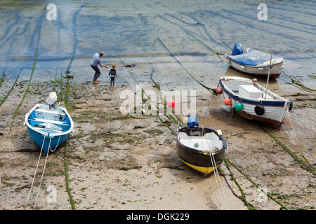 Father and son enjoy skimming stones at low tide in Mousehole Harbour Cornwall Stock Photo