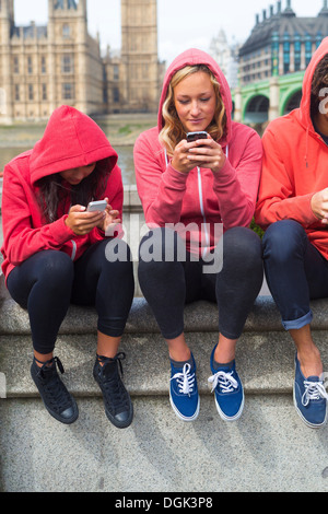 Three young people looking at mobile phones Stock Photo